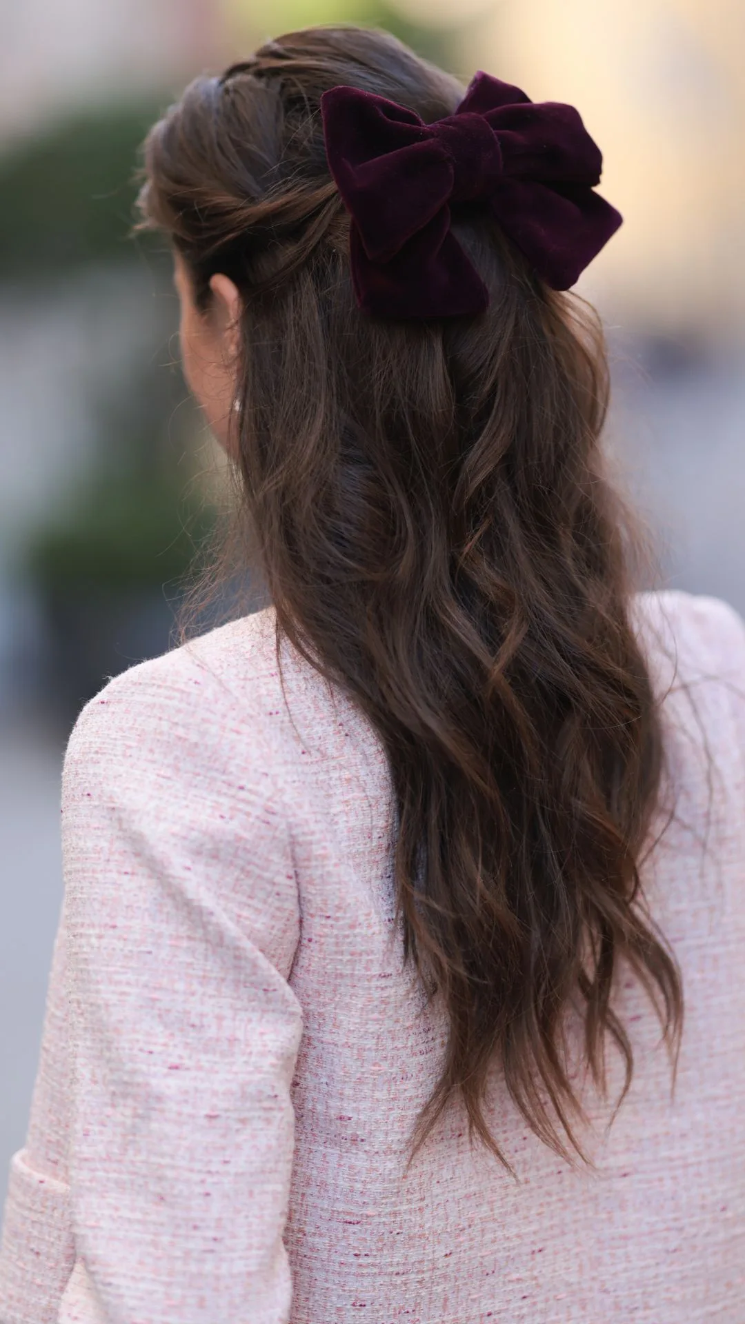 Carina Zavline is seen wearing a purple velvet bow in her wavy hair, and a cardigan in rose tweed from CocoVero.