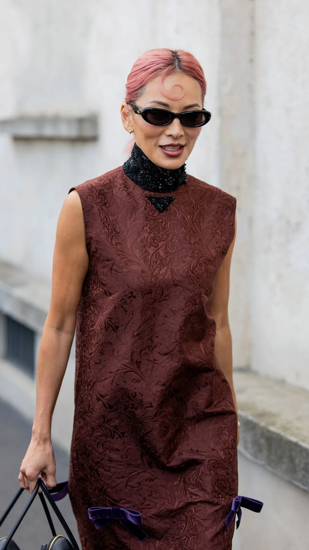 Tina Leung wears rust brown sleeveless dress, black bag, sunglasses outside Prada during Milan Fashion Week.