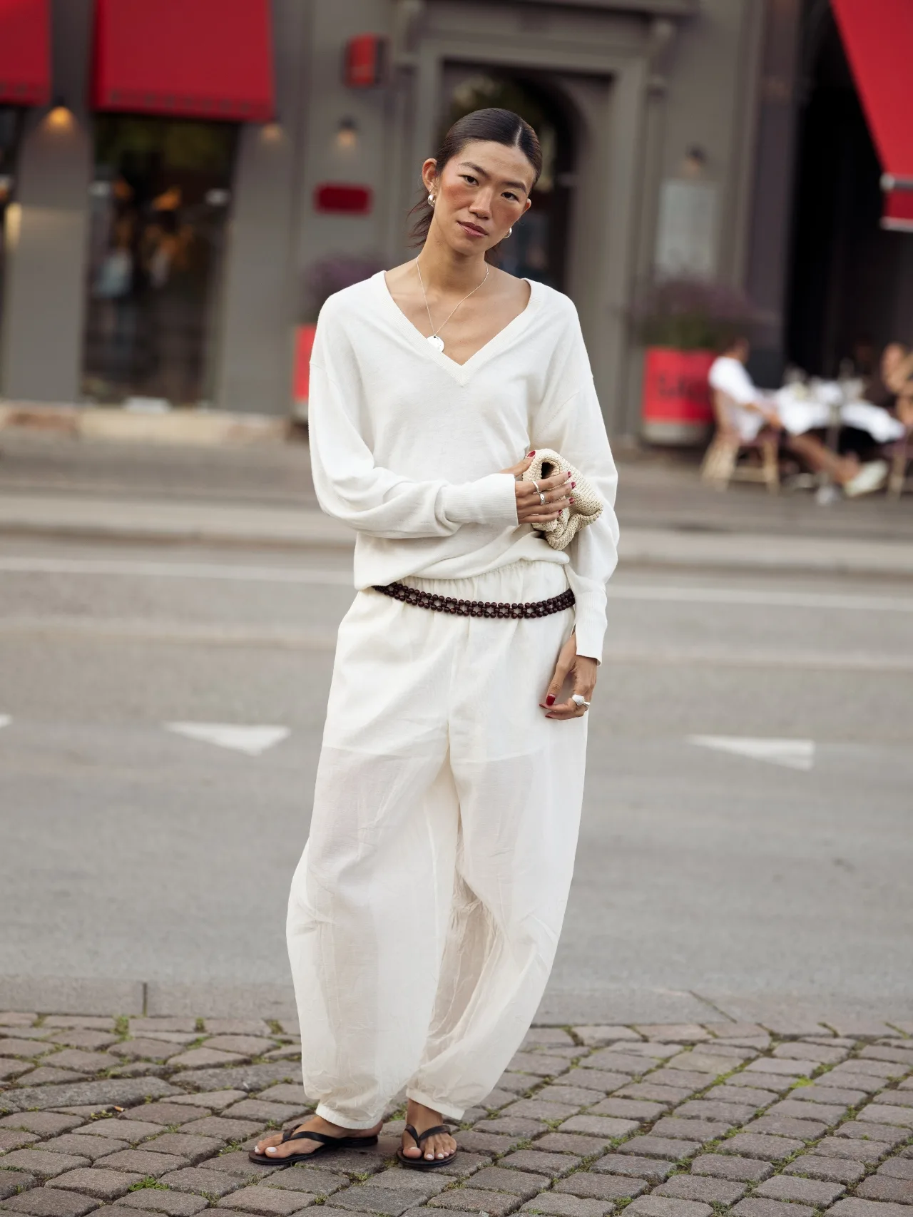 Woman wears all-white tshirt and sheer cotton trousers with black thongs