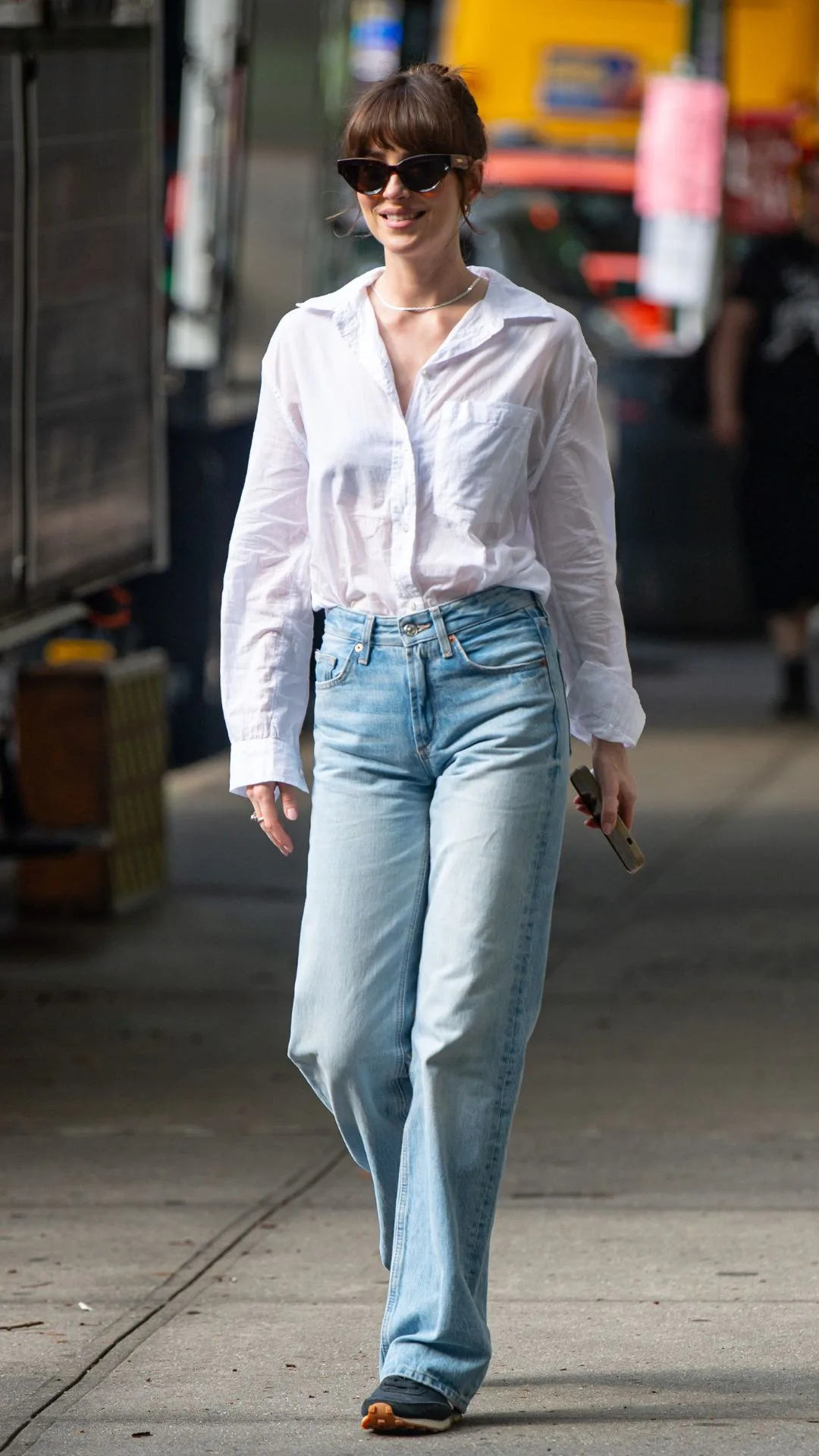 Woman wearing white shirt and blue jeans walking