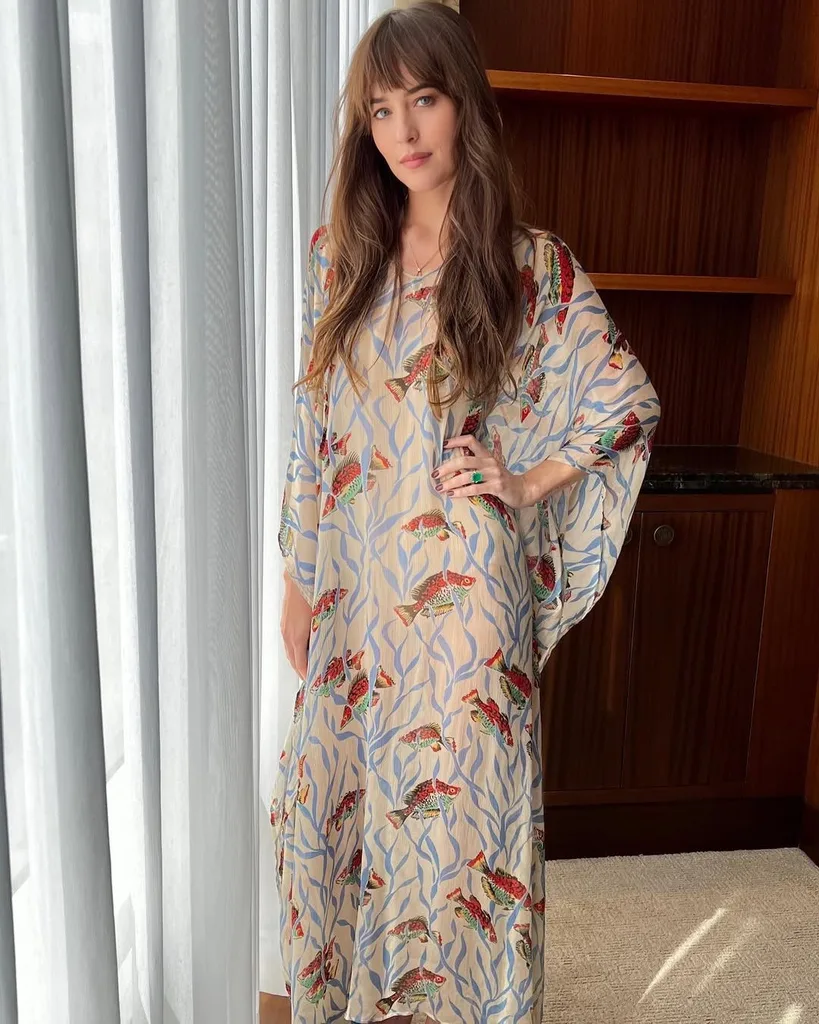 Woman wearing light blue patterned dress with hands on hip.