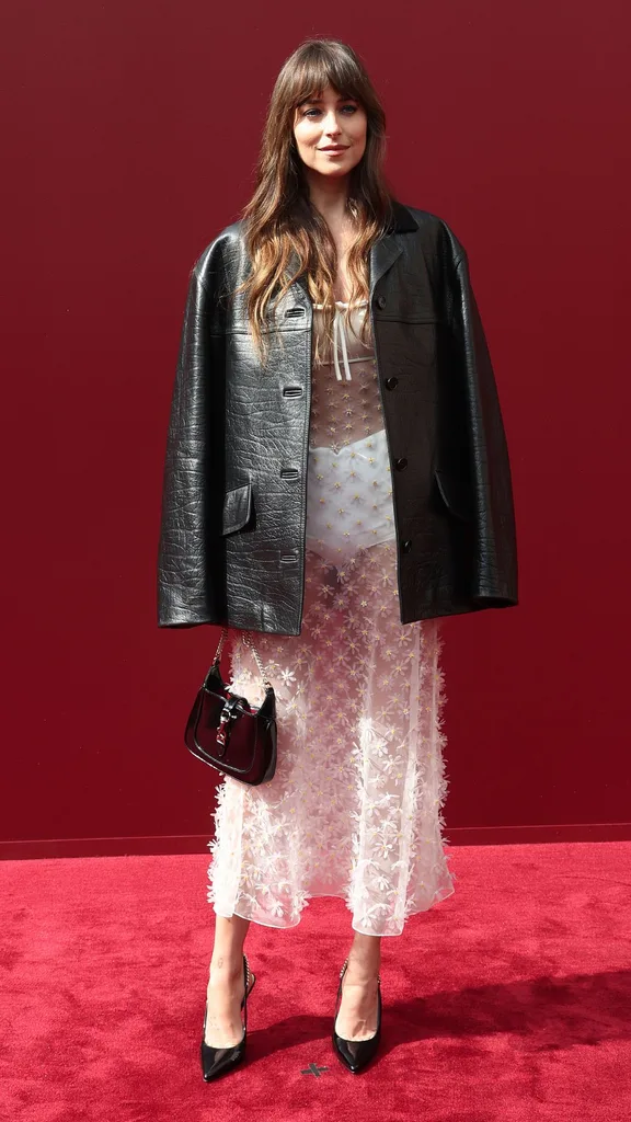 Woman wearing black leather jacket over sheer white dress.