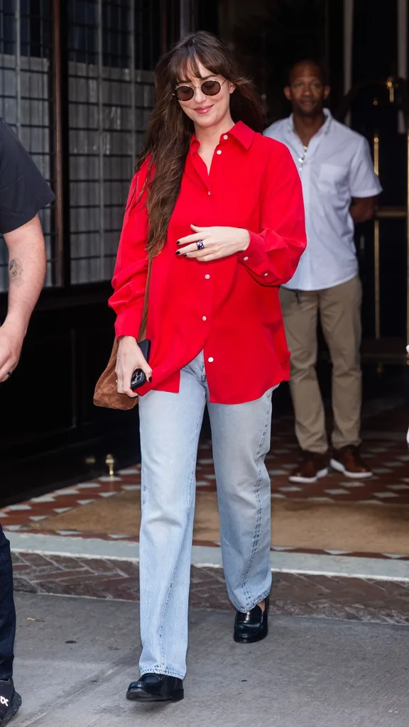 Woman wearing blue jeans and red shirt walking.