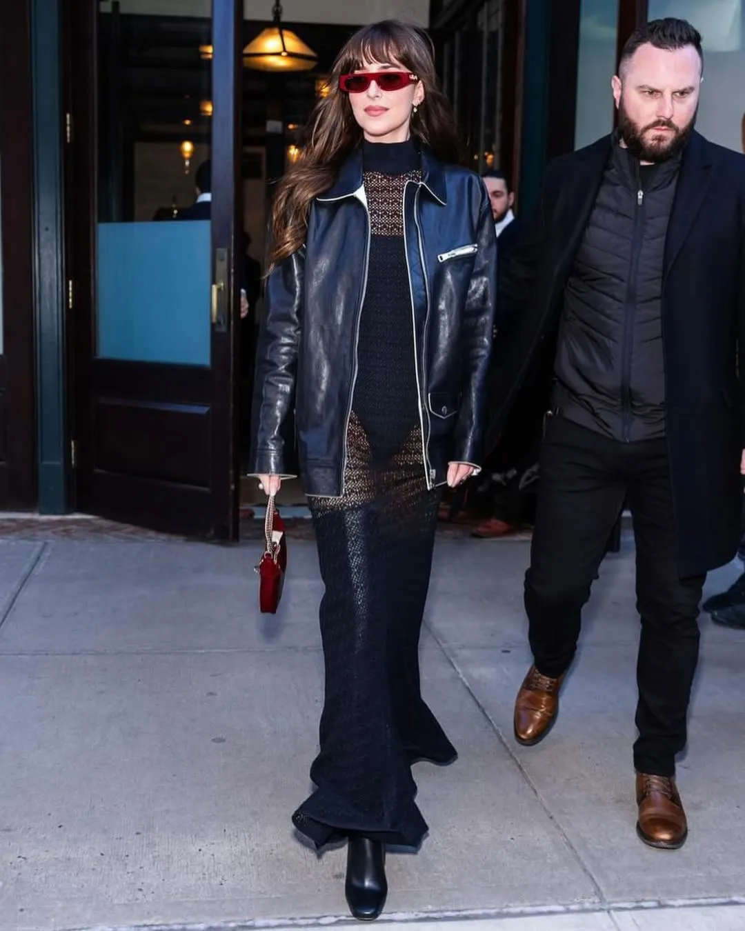 Woman wearing leather jacket over sheer black dress walking.