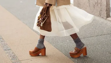 woman wearing clogs with a white skirt and grey socks
