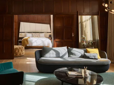 The Junior Suite at QT Sydney hotel. The image shows a living room with wooden paneling looking through to the bedroom in the distance.