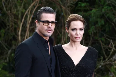 Two people in formal attire at an outdoor event, standing closely and looking towards the camera.