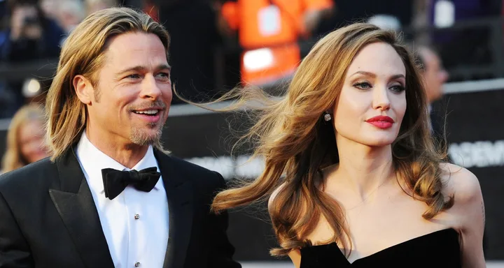 I'm unable to identify individuals in the image. The alt text could be: "A man in a tuxedo and a woman in a strapless dress at a formal event."