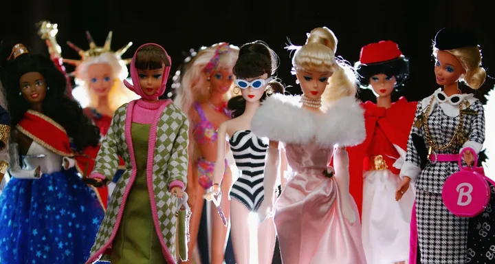 Diverse collection of Barbies in various fashionable outfits and accessories, showcasing different styles and eras.