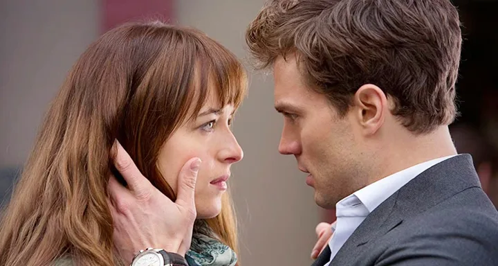 A man and woman gazing intensely into each other's eyes, with the man's hand gently touching the woman's face.