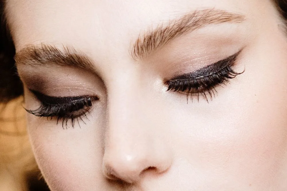 Close-up of closed eyes with bold eyeliner and thick eyelashes.
