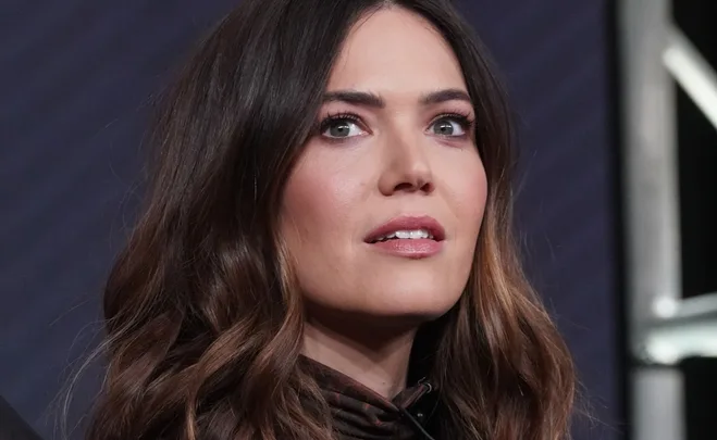 Woman with long brown hair and green eyes gazing upwards at an event.