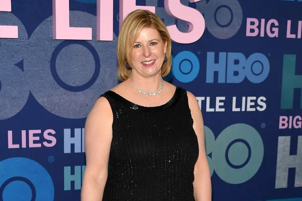 Woman in a black dress smiling at the "Big Little Lies" HBO event backdrop.