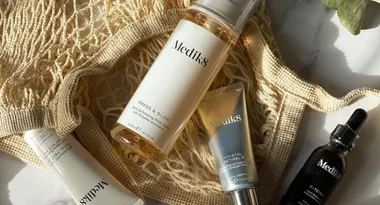 Medik8 skincare products arranged on a beige netted fabric.