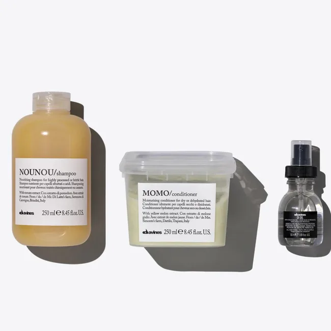 Davines hair products featuring NouNou shampoo, Momo conditioner, and hair oil, against a light gray background.