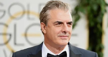A man in a suit and bow tie at a formal event with a blurred background.