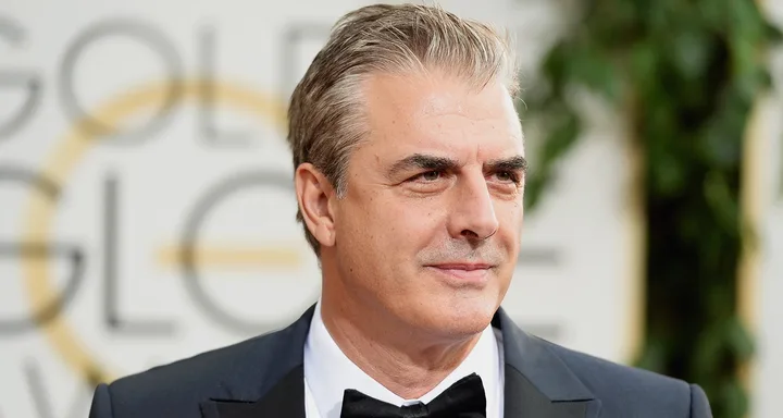 A man in a suit and bow tie at a formal event with a blurred background.