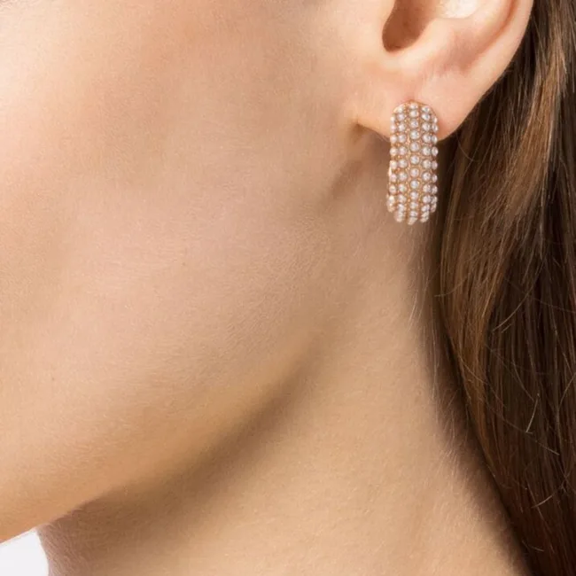 Profile of woman wearing gold hoop earrings with multiple rows of diamonds.