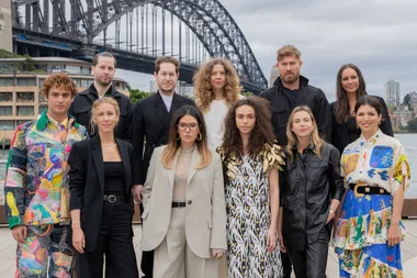 Group of people posing in front of Sydney Harbour Bridge, wearing colorful and stylish outfits.