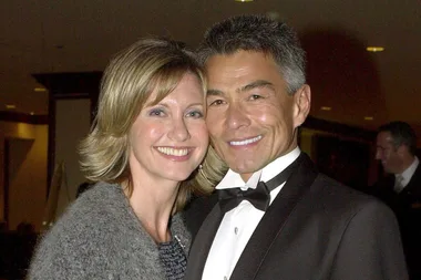 Couple smiling at an event, woman wearing a gray sweater and man in a tuxedo.