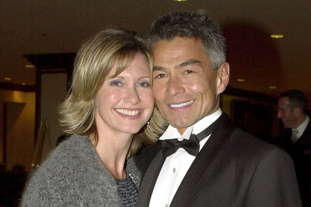 Couple smiling at an event, woman wearing a gray sweater and man in a tuxedo.