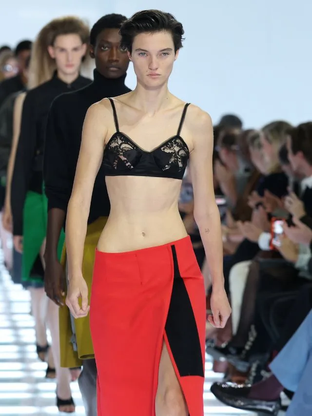 Model at Prada SS27 runway wears red skirt with black lace bra