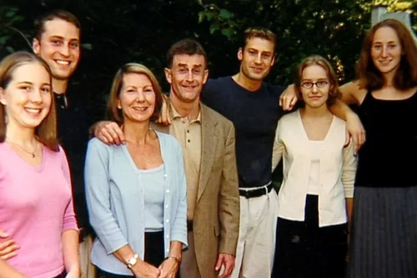 A group photo of seven people, three men and four women, standing closely together outdoors and smiling at the camera.