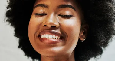 Smiling person with closed eyes and natural afro hairstyle.