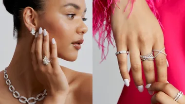 "Close-up of a person wearing diamond earrings, rings, and a necklace against a pink background."
