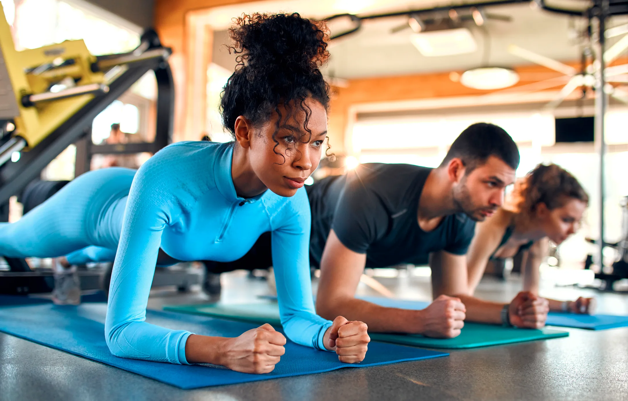 two women and a man doing a plank in Pilates