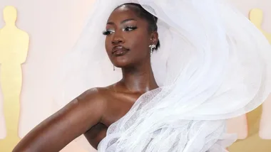Person in a white gown with dramatic tulle at a formal event, posing elegantly.