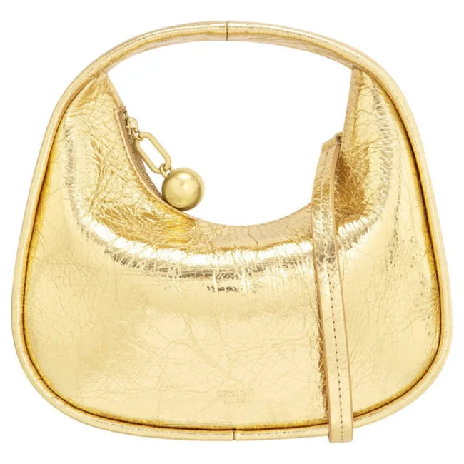 Golden metallic handbag with a curved handle and strap, featuring a spherical clasp detail.