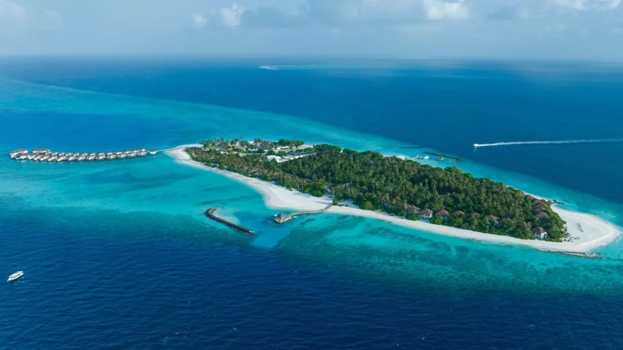 Aerial view of a tropical island with lush greenery, sandy beaches, turquoise water, and overwater bungalows in the Maldives.