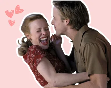 A woman laughing as a man playfully pretends to kiss her cheek against a pink background with heart doodles.