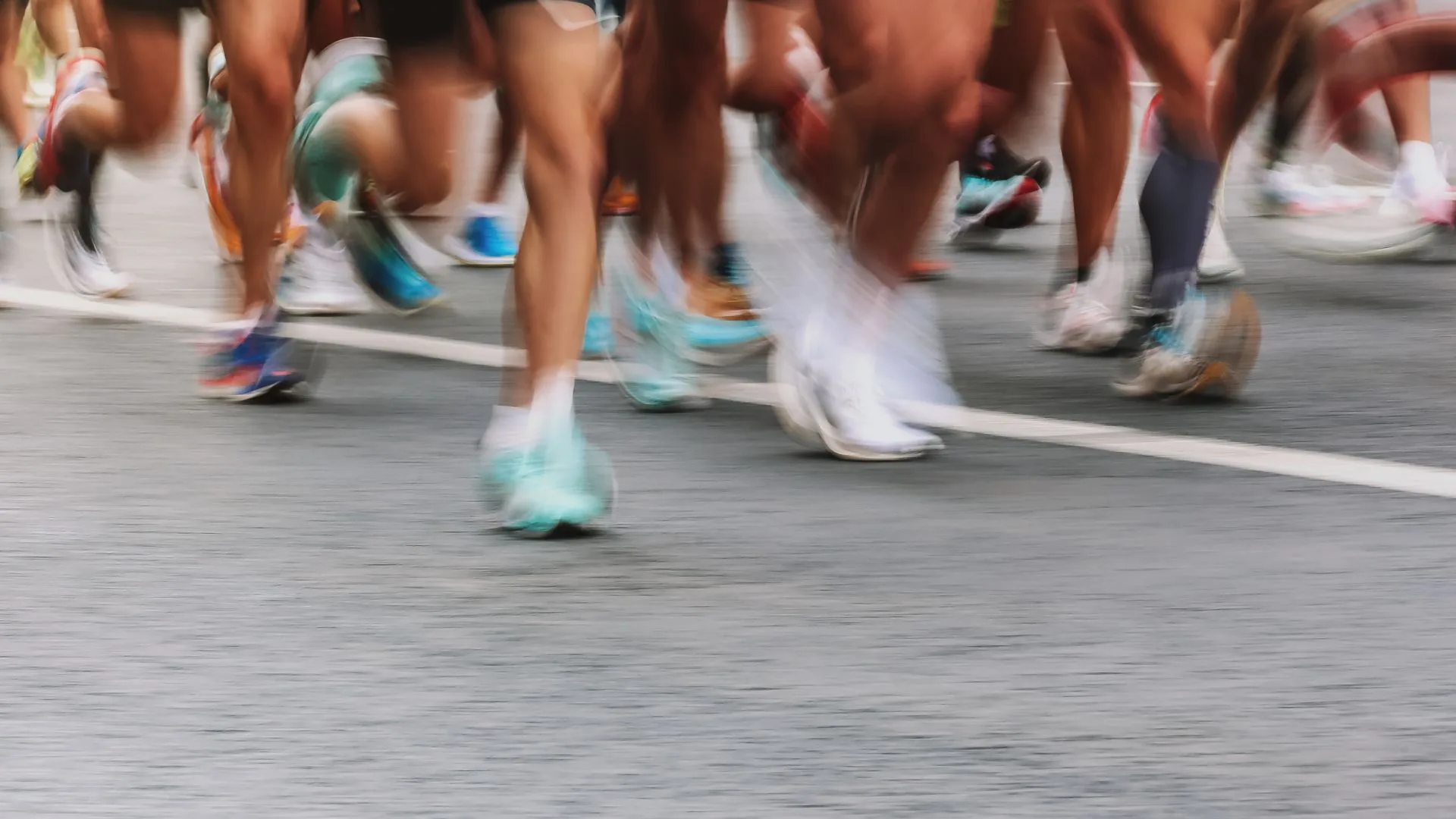 Blurred motion of runners' legs and colorful shoes during a street race.