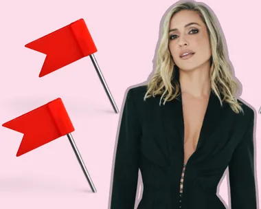 A woman in a black outfit stands surrounded by four red flags on a light pink background.