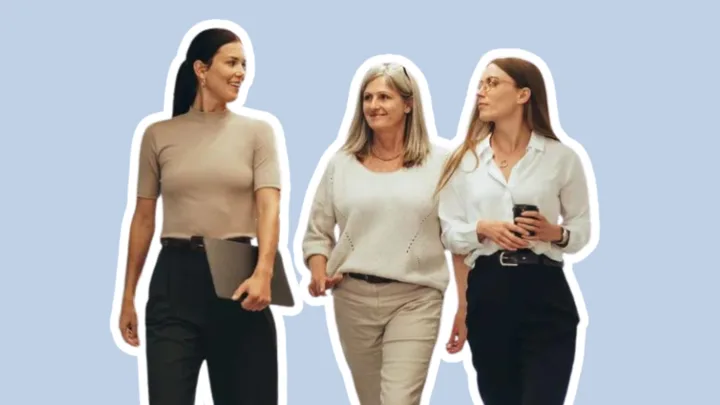 Three women walking and talking, one holding a laptop, another a smartphone, on a light blue background.