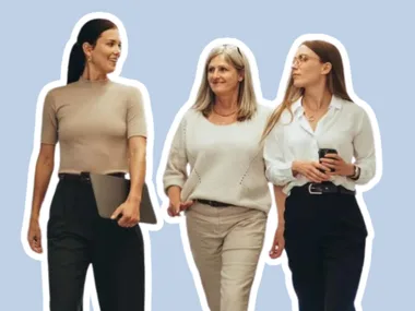 Three women walking and talking, one holding a laptop, another a smartphone, on a light blue background.