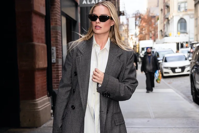 Margot Robbie in a smart casual outfit including oversized blazer and button shirt.