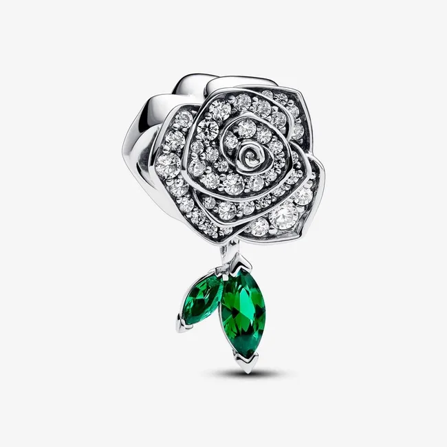 A sparkling rose-shaped jewelry piece with crystal details and two green gem leaves on a white background.