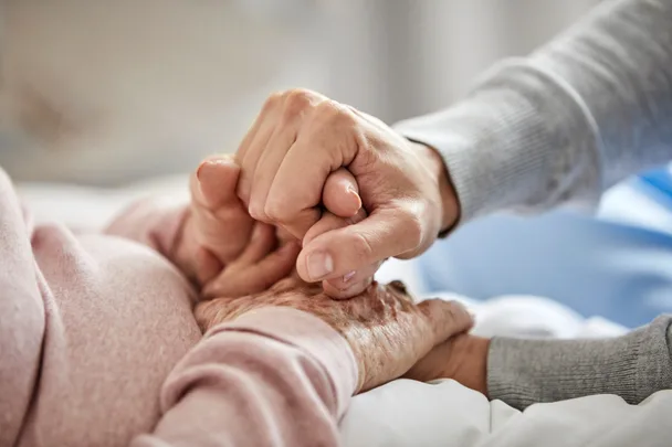 Two hands holding each other gently, expressing care and support.