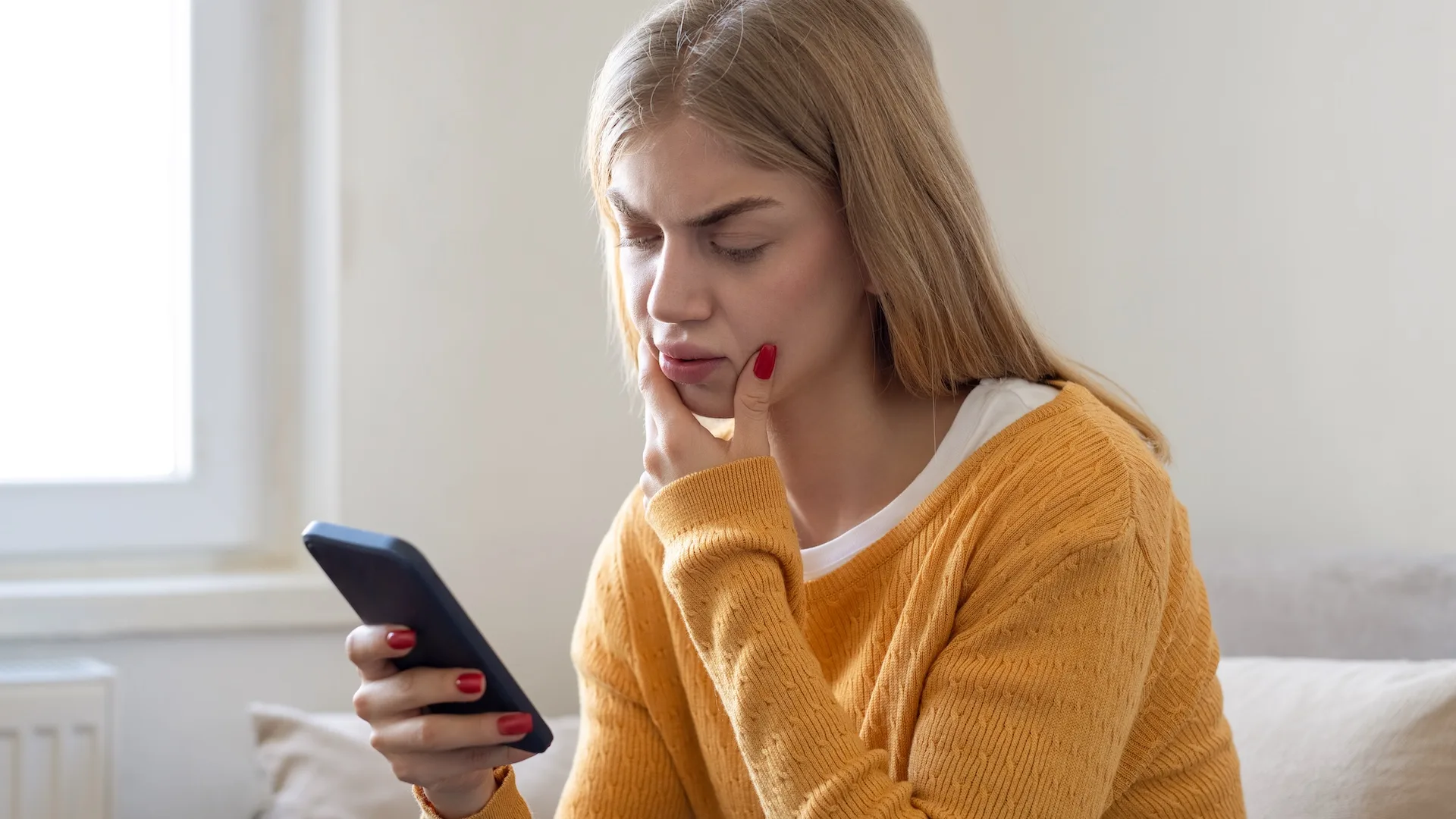 A woman looking at something on her phone with concern.