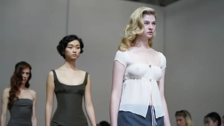 Models walking down the runway in elegant dresses at a fashion show.
