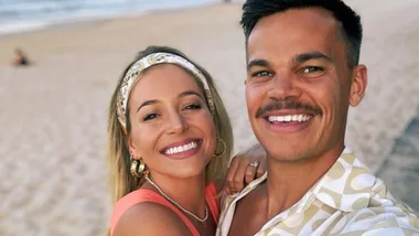 Couple smiling at the beach, with the woman wearing a headband and earrings.