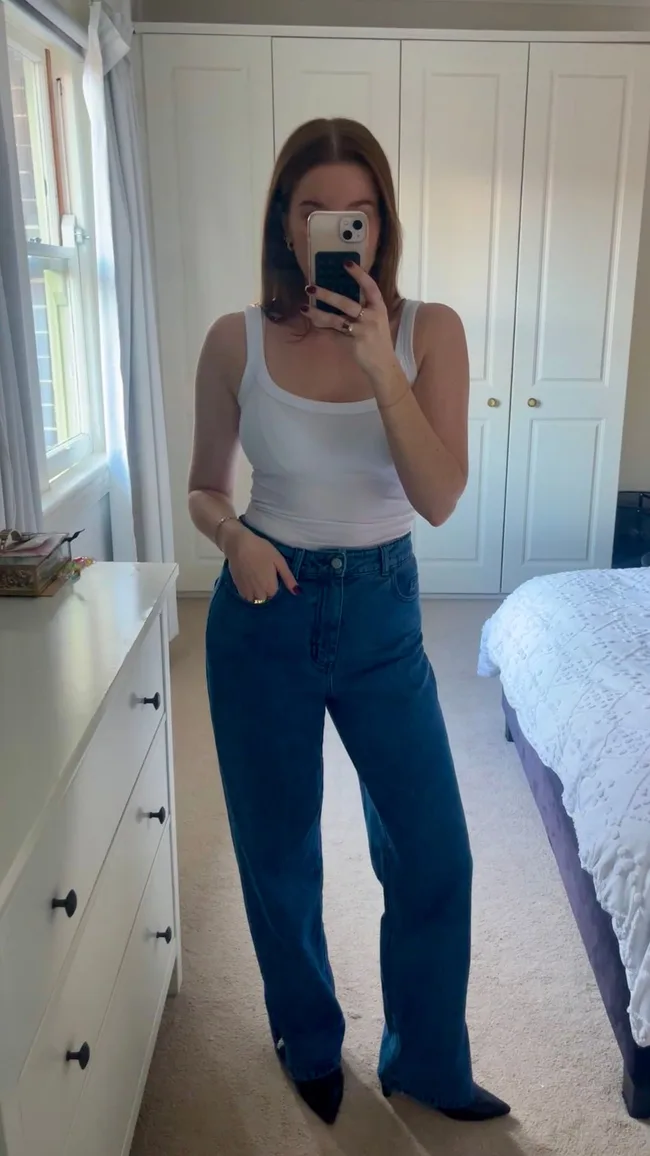 woman wears blue jeans and white tank