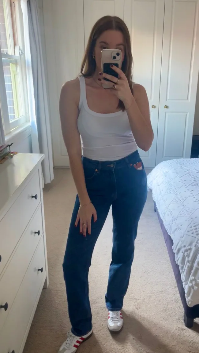 woman wears blue jeans and white tank