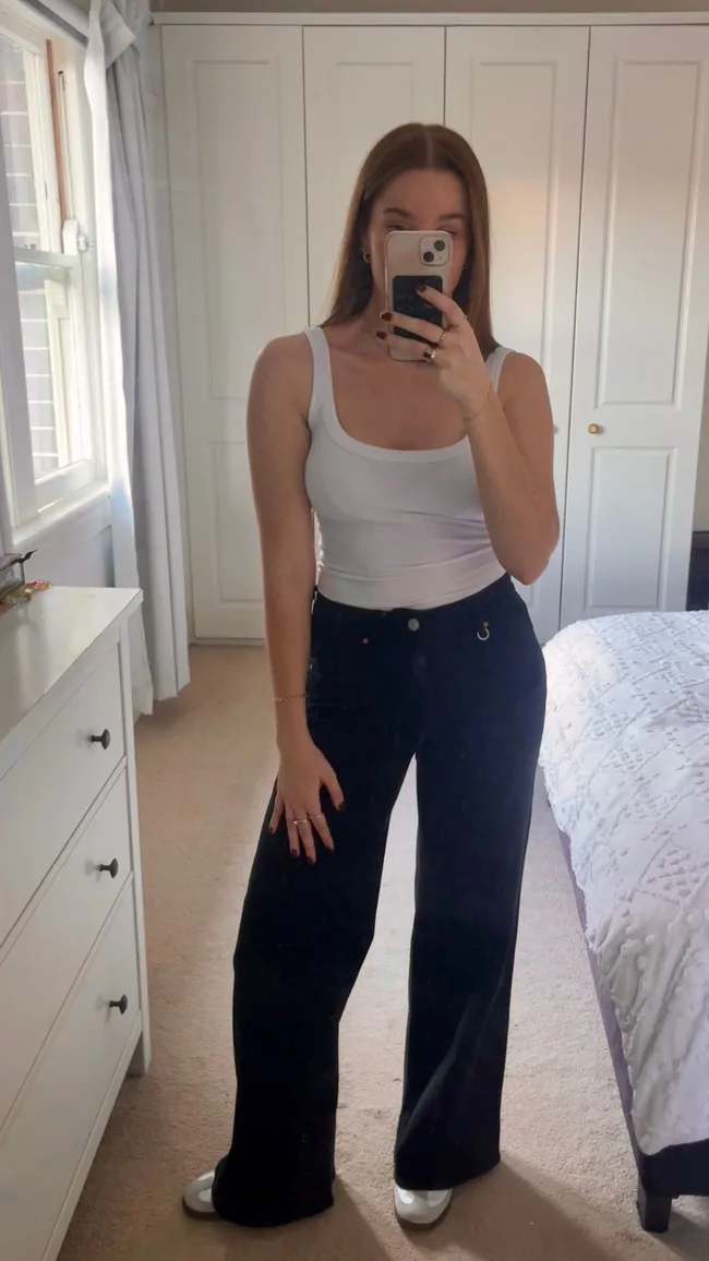 woman wears blue jeans and white tank