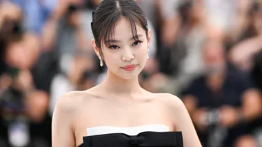 Person in a strapless black and white dress with a bow, standing, with blurred crowd in the background.