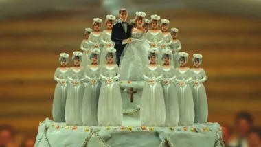 A teaser image from cult documentary 'keep sweet pray and obey' featuring a classic husband and wife wedding cake topper atop a cake, surreounded by more models of the wife doll.