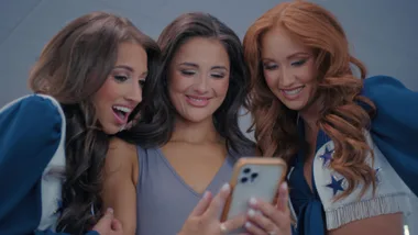 Three women smiling while looking at a phone
